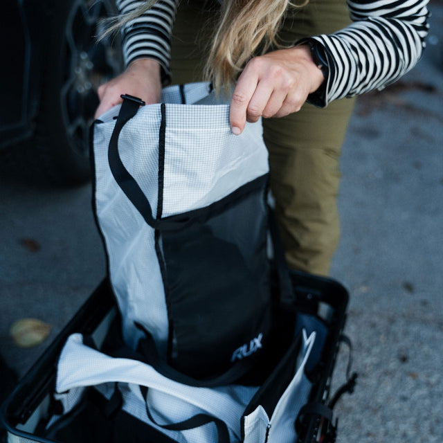Person packing a RUX mesh bag