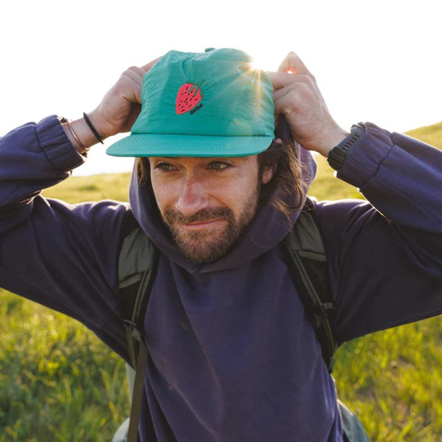 Model wearing green skida nylon cap with strawberry patch
