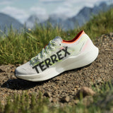 Adidas Terrex sneaker on a mountain trail with grass and mountains in the background