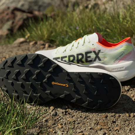 Close-up of a white and orange Terrex sneaker with black sole on a natural background