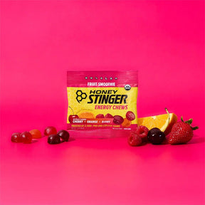 Honey Stinger energy chews package with fruit on a pink background