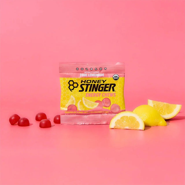 Honey Stinger energy chews package with lemon slices and red gummies on a pink background