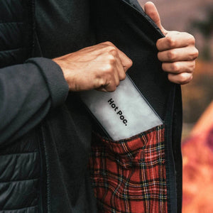 Person putting a Hot Poc body warmer in their jacket pocket
