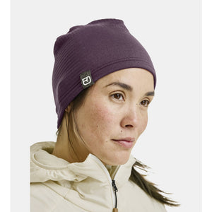 Woman wearing ortovox fleece light grid beanie in wild berry colour