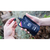 Person holding a Precision Fuel 90 gel container outdoors.