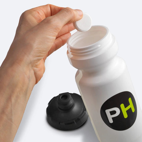 Hand putting a Precision Hydration electrolyte tablet into a water bottle