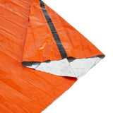 An orange reflective emergency blanket with a silver foil backing, folded to show its texture and reflective properties on the inside