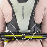 Back on-model view of green/grey Salomon ADV Skin 12 running vest with hiking poles attached