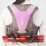 Back view of women's purple/grey Salomon ADV 12 running vest with poles attached