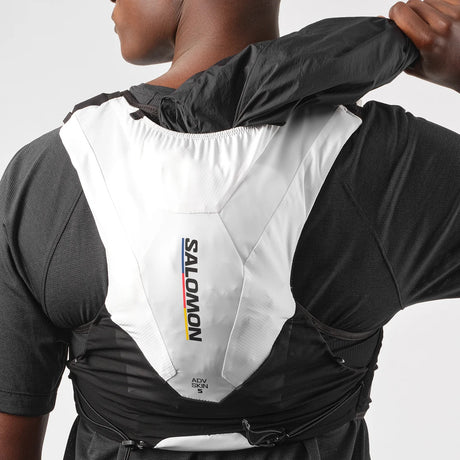 Person pulling a jacket out of the Salomon hydration vest they're wearing