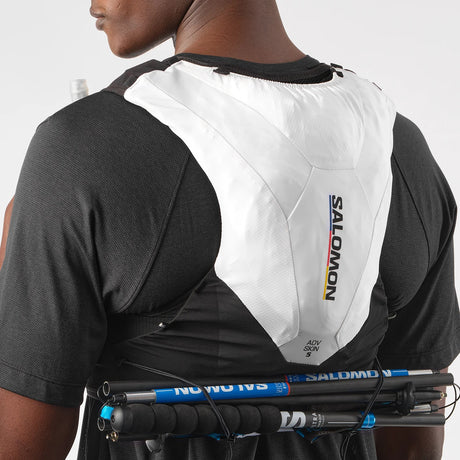 Person wearing a Salomon hydration vest with poles packed