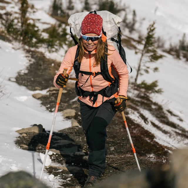 Person hiking on a mountain with a backpack and trekking poles