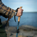Hand holding a hiking pole with a blurred natural background
