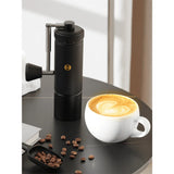 Timemore S3 ESP manual coffee grinder on a table with an espresso shot and coffee beans