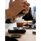A close-up lifestyle shot of a person making an espresso shot with the wacaco picopresso