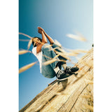Person sitting on a log with a clear blue sky and grass in the foreground