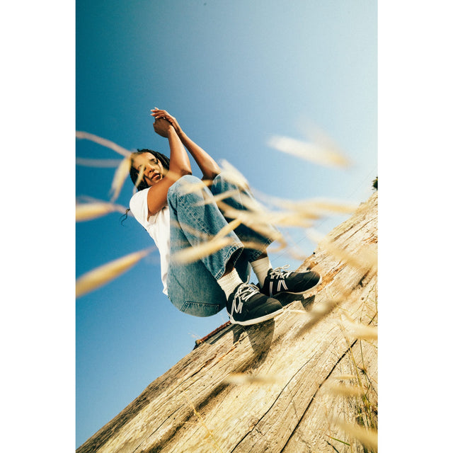 Person sitting on a log with a clear blue sky and grass in the foreground